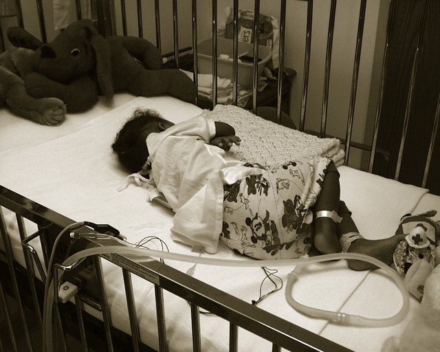 Sick baby in cot with tubes 
