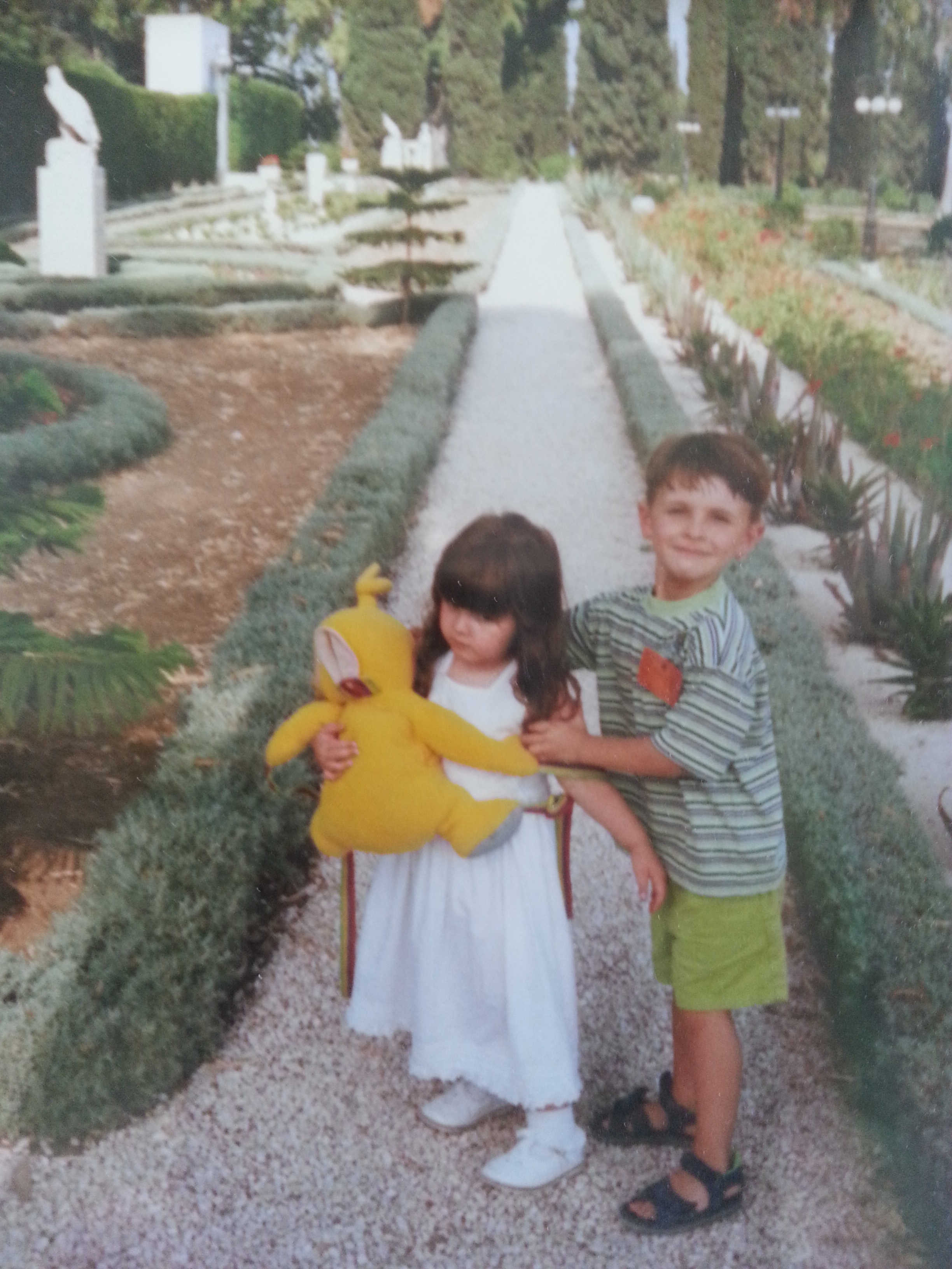 Farrah holding Lala (Teletubbie) with her brother trying to get her to look and smile at the camera in the gardens of Baha'u'llah in Akka, Israel